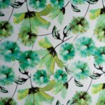 tela estampada con fondo blanco sobre el que se presentan flores de mediano gran tamaño en color verde